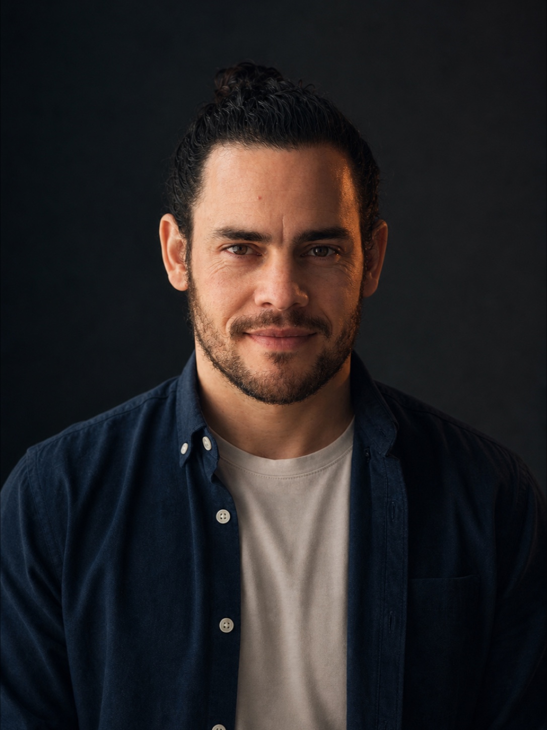 Tim Mudford, photographed in profile light against a dark room.